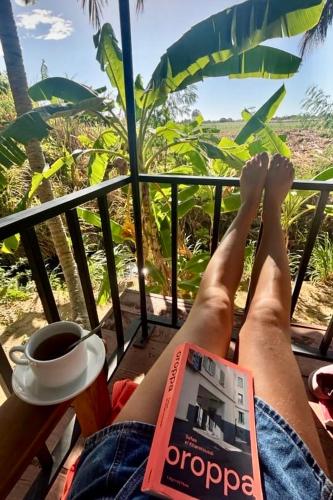 a person with their feet up on a balcony with a cup of coffee at coconut camp udawalawe in Dematapelessa