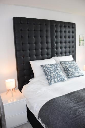 a bed with a black padded headboard and two pillows at Modern Flat - Leeds City Centre in Central Station