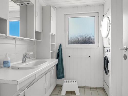 a white bathroom with a sink and a window at Holiday Home Myrte - 300m from the sea by Interhome in Blokhus