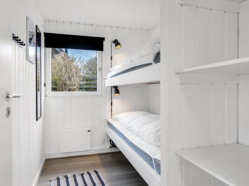 a small white room with a bed and a window at Holiday Home Myrte - 300m from the sea by Interhome in Blokhus