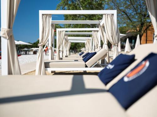 a row of white chairs with blue pillows on a beach at Sailors Village - Marina Monfalcone 