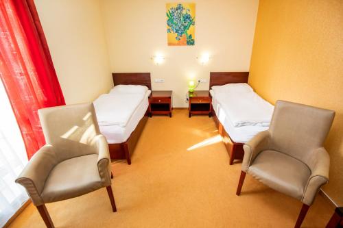 a hospital room with two beds and two chairs at Hotel Boss in Žilina