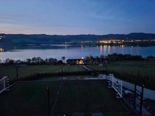 a tennis court next to a lake at night at Velo Active & Spa in Frydman