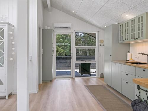 a kitchen with white cabinets and a large window at Holiday Home Ema - 1-9km from the sea by Interhome in Saltum