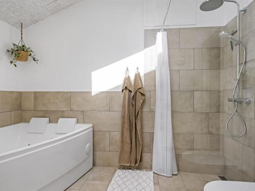a white bathroom with a tub and a shower at Holiday Home Ema - 1-9km from the sea by Interhome in Saltum