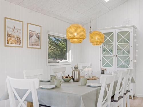 a white dining room with a table and white chairs at Holiday Home Ema - 1-9km from the sea by Interhome in Saltum