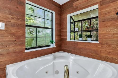 eine Badewanne in einem Zimmer mit 2 Fenstern in der Unterkunft Cozy Serenity - Outdoor Hot Tub, Firepit, Games, + Close to Downtown Gatlinburg in Glade