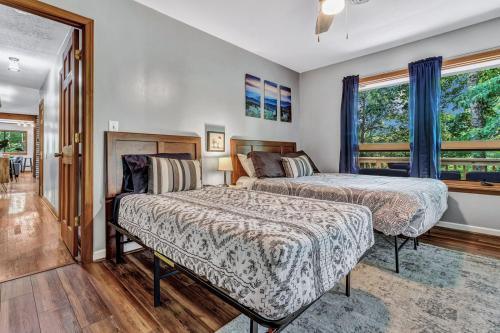 ein Schlafzimmer mit zwei Betten und einem Fenster in der Unterkunft Cozy Serenity - Outdoor Hot Tub, Firepit, Games, + Close to Downtown Gatlinburg in Glade