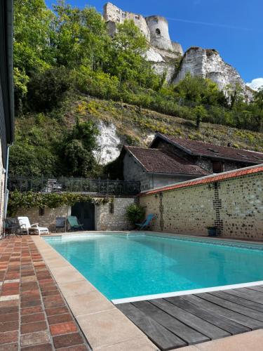 a swimming pool in front of a building with a mountain at Villa du Vieux Château in Les Andelys