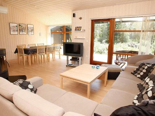 a living room with a couch and a tv and a table at Cozy Beach House with Spa - By Traum Ferienwohnungen in Torup Strand