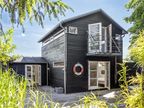 a black house with a balcony on a deck at Holiday Home Anouk - 500m from the sea by Interhome in Bindslev