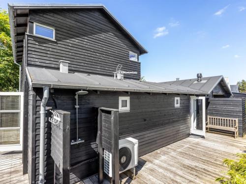 a black house with a deck with a porch at Holiday Home Anouk - 500m from the sea by Interhome in Bindslev