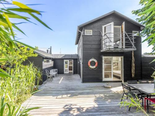 a black house with a deck with a table at Holiday Home Anouk - 500m from the sea by Interhome in Bindslev