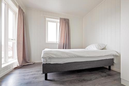 a bedroom with a bed with white sheets and a window at Seahouse with Panoramic Sea View in Vestvågøya