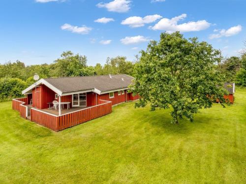 a red house in a field with a tree at Holiday Home Bruna - 300m from the sea by Interhome in Jerup
