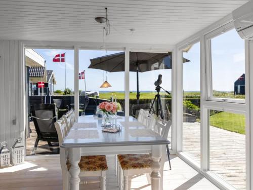 a white table with chairs and an umbrella on a patio at Holiday Home Reima - 50m from the sea by Interhome in Sæby
