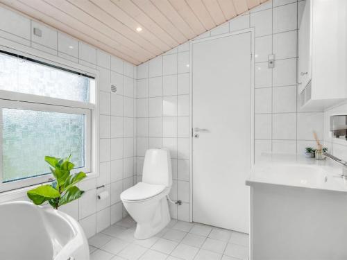 a white bathroom with a toilet and a window at Holiday Home Adrienne - 240m from the sea by Interhome in Hirtshals