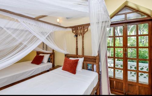 two beds in a room with a window at Garden Beach Villa Zanzibar in Kilima Juu Pwani