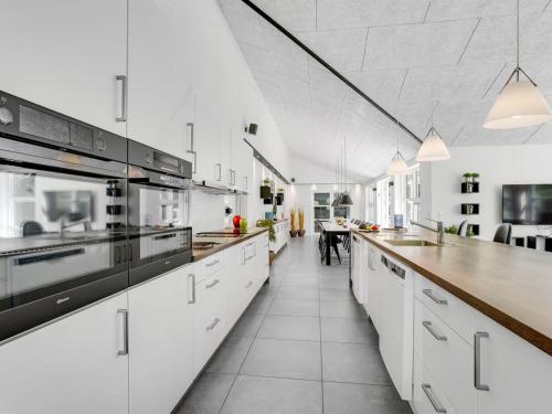 a large white kitchen with white cabinets and a counter at Holiday Home Patrice - 300m from the sea by Interhome in Strøby