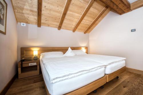 a bedroom with a large white bed with a wooden ceiling at Sertorelli Sporthotel in Breuil-Cervinia