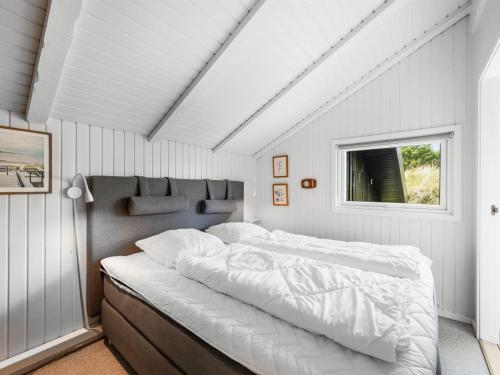 a bedroom with a large white bed with a window at Holiday Home Emin - 700m from the sea by Interhome in Vejers Strand