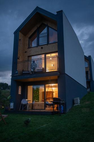 a house with a balcony and a table in the yard at StyLove Domki 1 in Kluszkowce