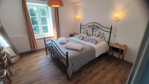 Un dormitorio con una cama grande con sábanas y almohadas blancas. en La goutelle, en Neufmanil