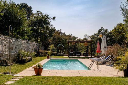 a swimming pool in a yard with chairs and an umbrella at Casa de Campo do Telhado Caldelas in Caldelas