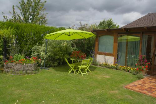 a green table and chair under an umbrella in a yard at Les Rendzines in Nuisement-sur-Coole