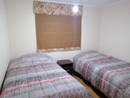 a bedroom with two beds and a window at Pucón, casa en parcela in Pucón