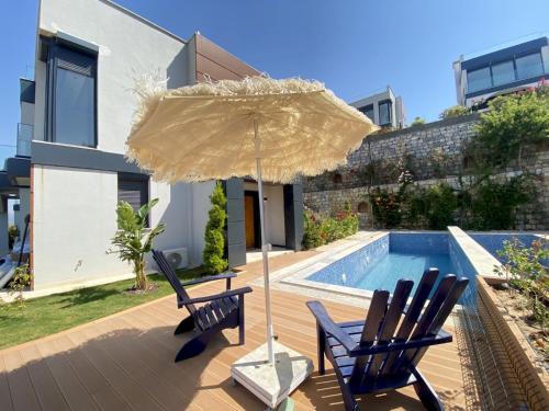 a patio with two chairs and an umbrella next to a pool at Luxury Villa w Private Pool Panoramic View in Bogazici