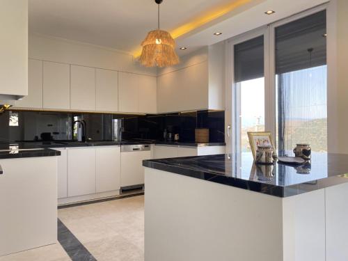 a kitchen with white cabinets and a black counter top at Luxury Villa w Private Pool Panoramic View in Bogazici