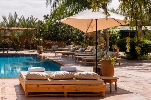 a bed with an umbrella next to a pool at Hacienda de Julie in Sraïri