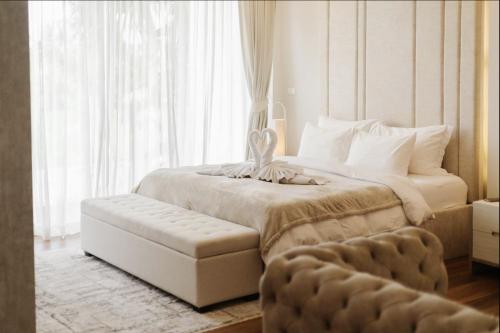 a bedroom with a large bed with a bench next to a window at Palm Villa - Award Winning Modern Luxury & Exclusive Villa in Chiang Mai
