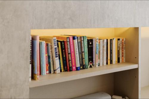 a row of books on a shelf at Palm Villa - Award Winning Modern Luxury & Exclusive Villa in Chiang Mai