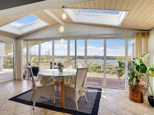 a dining room with a table and chairs and windows at Holiday Home Annabeth - 300m to the fjord by Interhome in Løgstrup