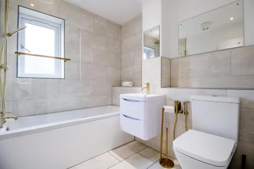 a bathroom with a toilet and a tub and a sink at Beautiful and Cosy 4-bed Home in Milton Keynes by Renzo, Driveway, Close to M1 in Milton Keynes