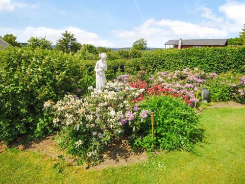 a statue in the middle of a garden with flowers at Holiday Home Annabeth - 300m to the fjord by Interhome in Løgstrup