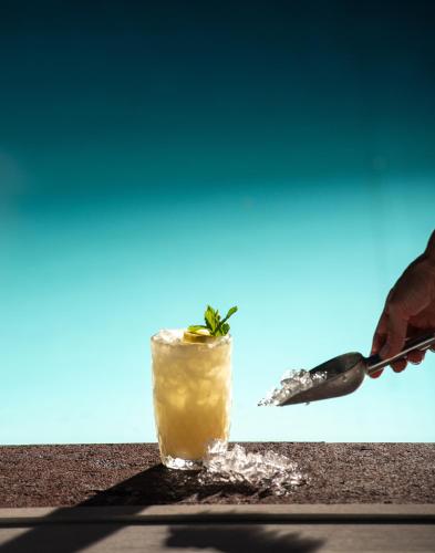 a drink on a table with a person holding a spoon at Karavia Lux Inn in Afissos