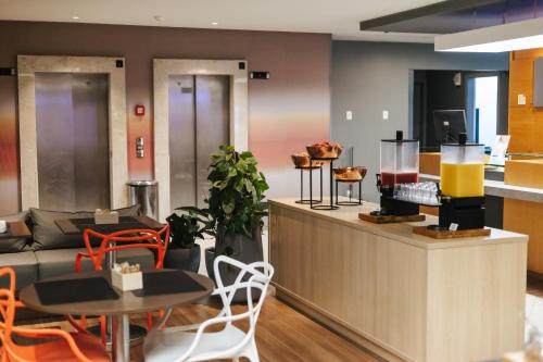 a restaurant with a counter with a table and chairs at Aéra São José Floripa in São José