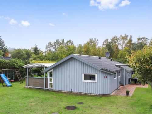 a gray shed with a playground in a yard at Holiday Home Albertina - 200m from the sea by Interhome in Hals