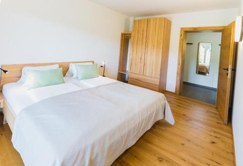 a bedroom with a large white bed and wooden floors at Seespitz 37 - Ferienwohnungen Eisendle in Seeboden