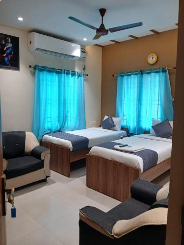 a room with three beds and a couch and blue curtains at Greenapple Residency in Chennai