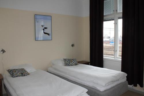 two beds in a room with a window at Stationshusets Hotell och Café in Köping