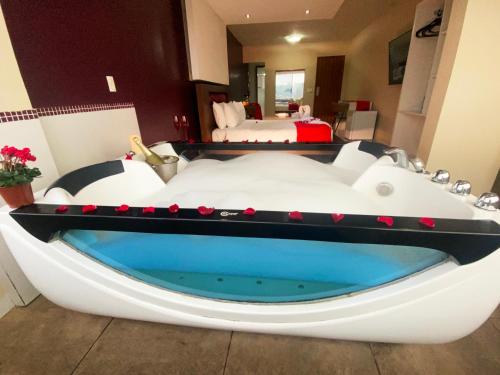 a large bath tub in a room with a bed at Emirates Hotel & Suites in Santana do Livramento