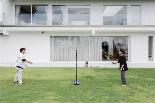 two men playing a game of tee ball in a yard at Palm Villa - Award Winning Modern Luxury & Exclusive Villa in Chiang Mai