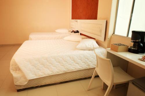 a bedroom with two beds and a chair in it at Emirates Hotel & Suites in Santana do Livramento