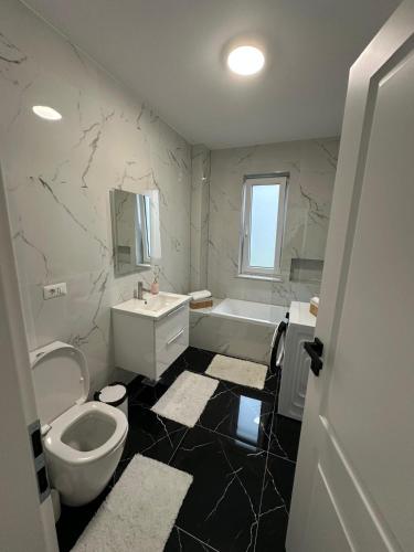 a bathroom with a toilet and a sink and a tub at Apartament Calea Bucovinei in Rădăuţi
