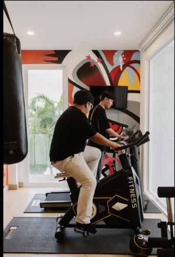 two men riding an exercise bike in a gym at Palm Villa - Award Winning Modern Luxury & Exclusive Villa in Chiang Mai