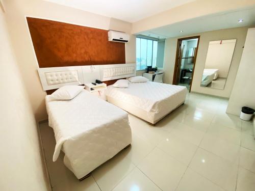 a hotel room with two beds and a mirror at Emirates Hotel & Suites in Santana do Livramento